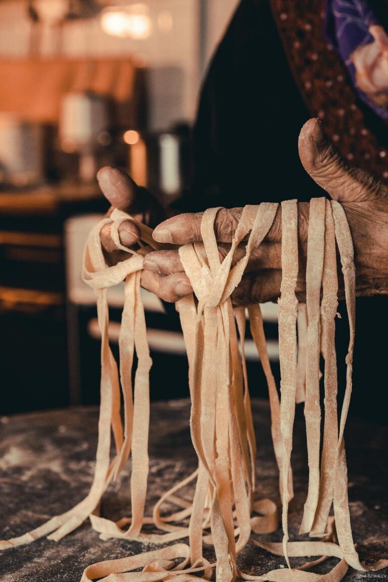 Fresh handmade pasta resting on a chef's hands