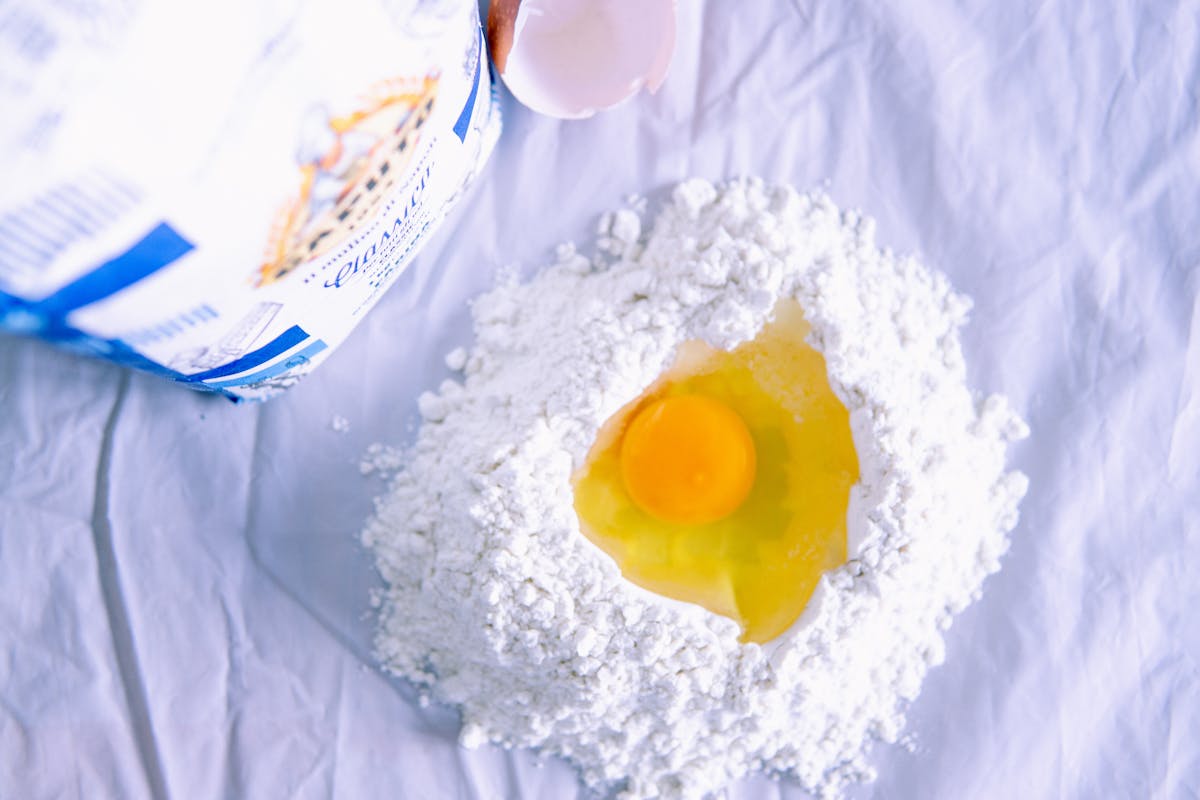 Eggs, flour, and fresh pasta on a kitchen surface