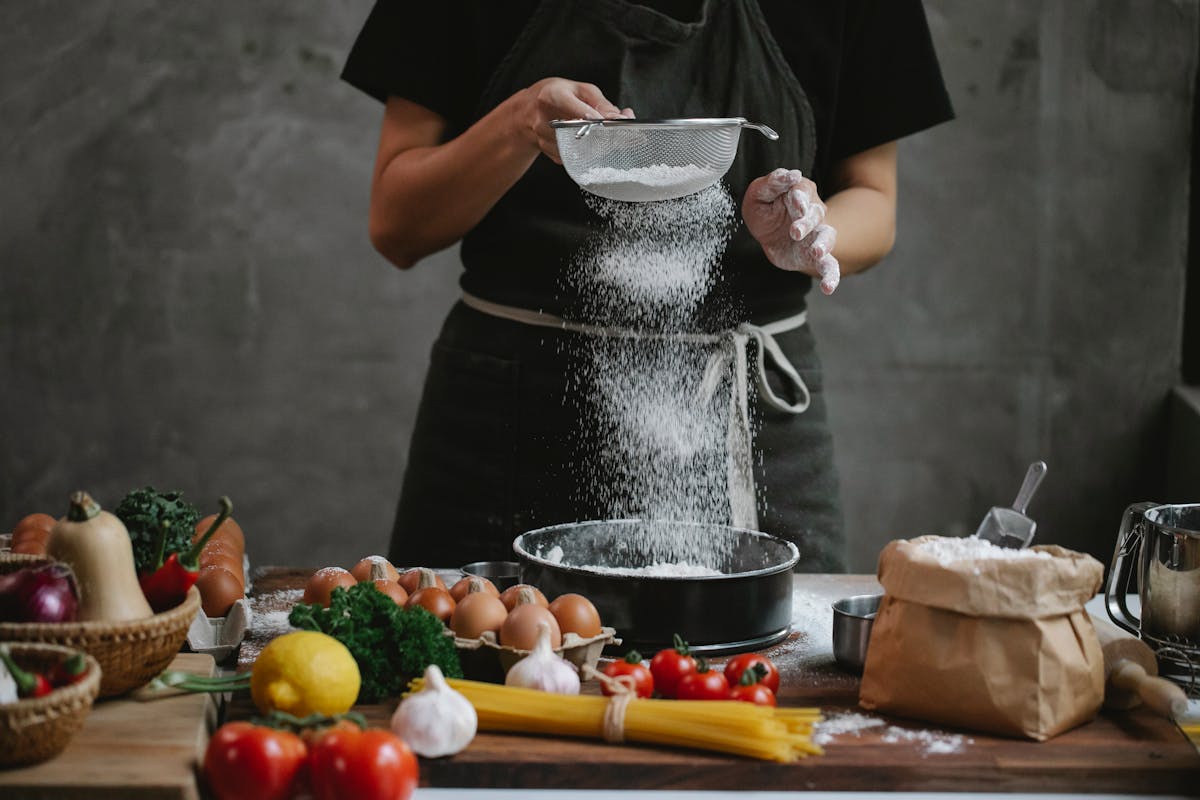 Chef sifting flour through a sieve for fresh pasta dough